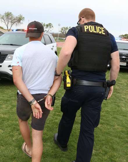 A Lemoore police officer handcuffs suspect Anthony Jones, an important part of Every 15 Minutes. He is taken to the Kings County Jail before returning to the school.